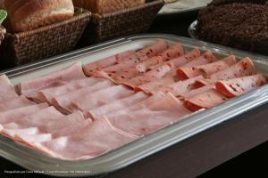a tray of ham on a table with bread at Hotel Princeton in Piracicaba