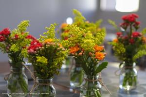 four glass vases filled with flowers on a table at Hotel Princeton in Piracicaba