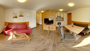 un soggiorno con divano rosso e tavolo di Karglhof Stammhaus a Faak am See