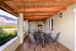 a patio with a table and chairs and a fireplace at Bon Accord Farm Cottages in Montagu