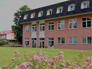un edificio con flores rosas delante de él en Vzdělávací Středisko a Hotel, en Varnsdorf