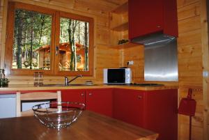 a kitchen with red cabinets and a table in a cabin at Bungalows da Peneda in Lamas de Mouro