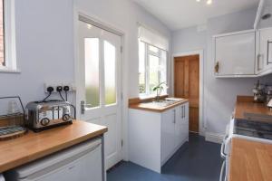 een keuken met witte kasten, een wastafel en een raam bij Johnson Road Near Erdington Station in Birmingham