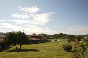 a green yard with trees and houses in the background at Due Lune Puntaldia Resort & Golf in San Teodoro
