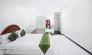 ein Schlafzimmer mit einem großen weißen Bett und einem grünen Kissen in der Unterkunft Treebo Trend Omni Palace in Indore