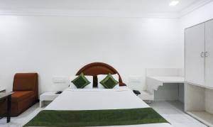 ein Schlafzimmer mit einem großen weißen Bett und einem Stuhl in der Unterkunft Treebo Trend Omni Palace in Indore