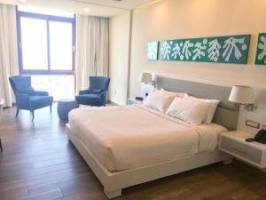 a hotel room with a bed and two blue chairs at Satama Hotel in Cap-Haïtien