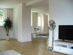 a living room with a flat screen tv and a fan at Ferienwohnung Riedner in Lüneburg