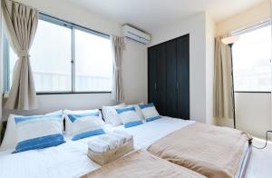 a bedroom with a large white bed with blue pillows at Nishikamata ColorBee House in Tokyo