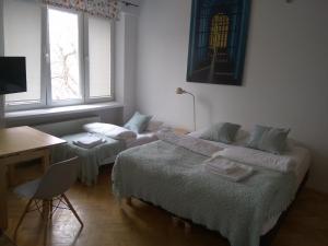 two beds in a room with a desk and a desk at Studio Iwicka in Warsaw