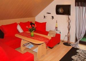 uma sala de estar com um sofá vermelho e uma mesa em Gemütliche Ferienwohnung im Thüringer Wald, nahe des Rennsteigs - pure Erholung em Schmiedefeld am Rennsteig