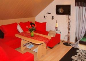 Una sala de estar con un sofá rojo y una mesa. en Gemütliche Ferienwohnung im Thüringer Wald, nahe des Rennsteigs - pure Erholung, en Schmiedefeld am Rennsteig