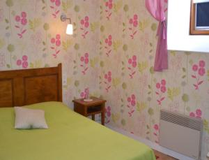 a bedroom with a green bed and pink floral wallpaper at Ferme de la Lande Martel in Juilley