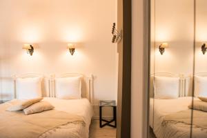 a bedroom with two beds with white pillows and a mirror at Les suites du 17 in Aigues-Mortes