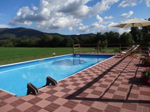 a large swimming pool with an umbrella and chairs at Valle degli Arci in Castel Madama