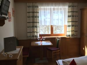ドルフガシュタインにあるHaus Schnepfleitnerのテーブルと窓(ワイングラス付)が備わる客室です。