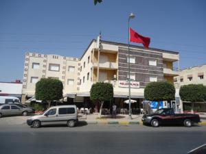 two cars parked in front of a building with a red flag at Hotel Azul Palace in Sidi Yahia el Gharb