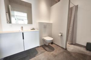 a white bathroom with a toilet and a sink at Hotel Phønix in Holstebro