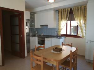 a kitchen with a wooden table and a table and chairs at Apartamentos Colmado in Sanxenxo