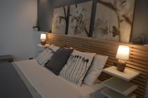 un letto bianco con cuscini sopra di UP&B Rooms Catania a Mascalucia