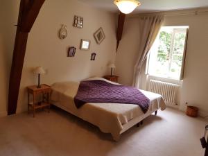 um quarto com uma cama grande e uma janela em La Taille de Biou em Huisseau-sur-Cosson