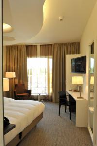 ウーデンにあるHotel Udens Duynのベッドとデスクが備わるホテルルームです。
