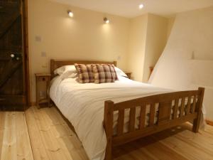 a bedroom with a large bed with white sheets at Pershbrook Cottage & Garden in Oakle Street