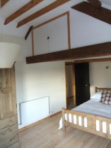 a bedroom with a large bed and wooden floors at Pershbrook Cottage & Garden in Oakle Street