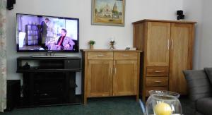 a living room with a flat screen tv and wooden cabinets at Ferienwohnung an der Almequelle in Alme