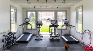a gym with several tread machines in a room with windows at Baron's Cove in Sag Harbor