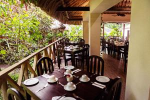 a dining area with tables and chairs and umbrellas at Hotel Jungle Lodge Tikal in Tikal