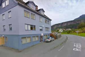 a white house with a car parked in the street at Apartment in Herand, Hardanger in Herand