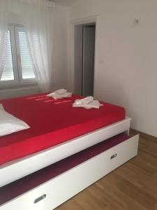 a bedroom with a bed with red sheets and a window at Apartment Doma in Međugorje