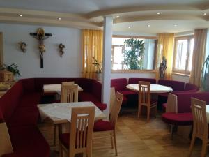 a restaurant with tables and chairs and a cross on the wall at Pension Wallnöfer in Mieming
