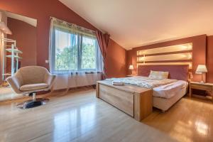 a bedroom with a bed and a chair and a window at Villa EverGreen near the city center with private garden, hot tub, garage parking, patio in Vilnius +20 photos