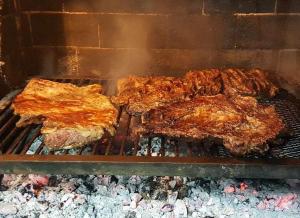 a group of ribs are cooking on a grill at Chacras de Coria desde Berdina casa loft privada para 4 con jardín, parrilla y cochera a 5 min a pie de la plaza principal in Chacras de Coria