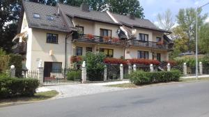 uma casa com uma cerca em frente em Pokoje gościnne Pod Lwami em Kudowa-Zdrój