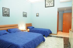 Dos camas en una habitación con edredones azules. en Affittacamere Conte Di Cavour, en Noto