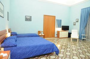 Dormitorio azul con cama y TV en Affittacamere Conte Di Cavour, en Noto