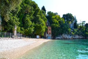 a beach with trees and a building on the shore at Apartment Antonija with seaview in Rijeka