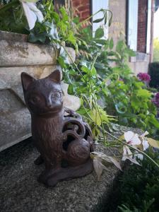 une statue d'un chat assis sur une marche dans l'établissement maison courbarien, à Saint-Georges-la-Pouge