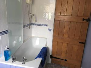 a bathroom with a tub and a sink and a door at Canol y Llan in Machynlleth