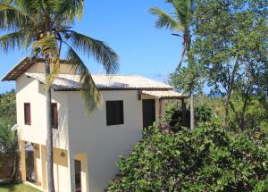 ein weißes Haus mit Palmen davor in der Unterkunft Chalés Nascer do Sol in Diogo