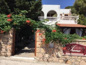 a house with a stone wall with red flowers at Studios Irene in Skala