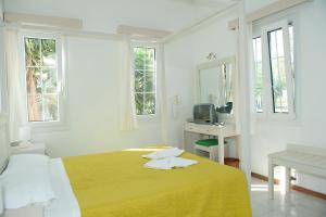 Habitación blanca con cama, escritorio y ventanas en Samos Apartments, en Marathokampos