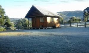 un pequeño edificio de madera en un campo con una valla en Cantinho do Sossego, en Urubici