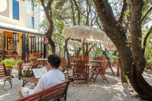 a woman sitting on a bench reading a book at Hotel Villa Lo Scoglietto in San Vincenzo