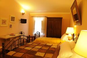 a bedroom with two beds and a table and a window at La Casa Di Babbai in Nuchis