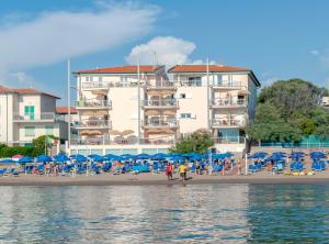 a beach with chairs and umbrellas and a building at Residence Villa Lo Scoglietto in San Vincenzo