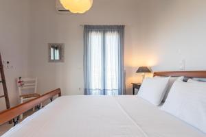 a bedroom with a large white bed and a window at Milian Suite in Adamantas